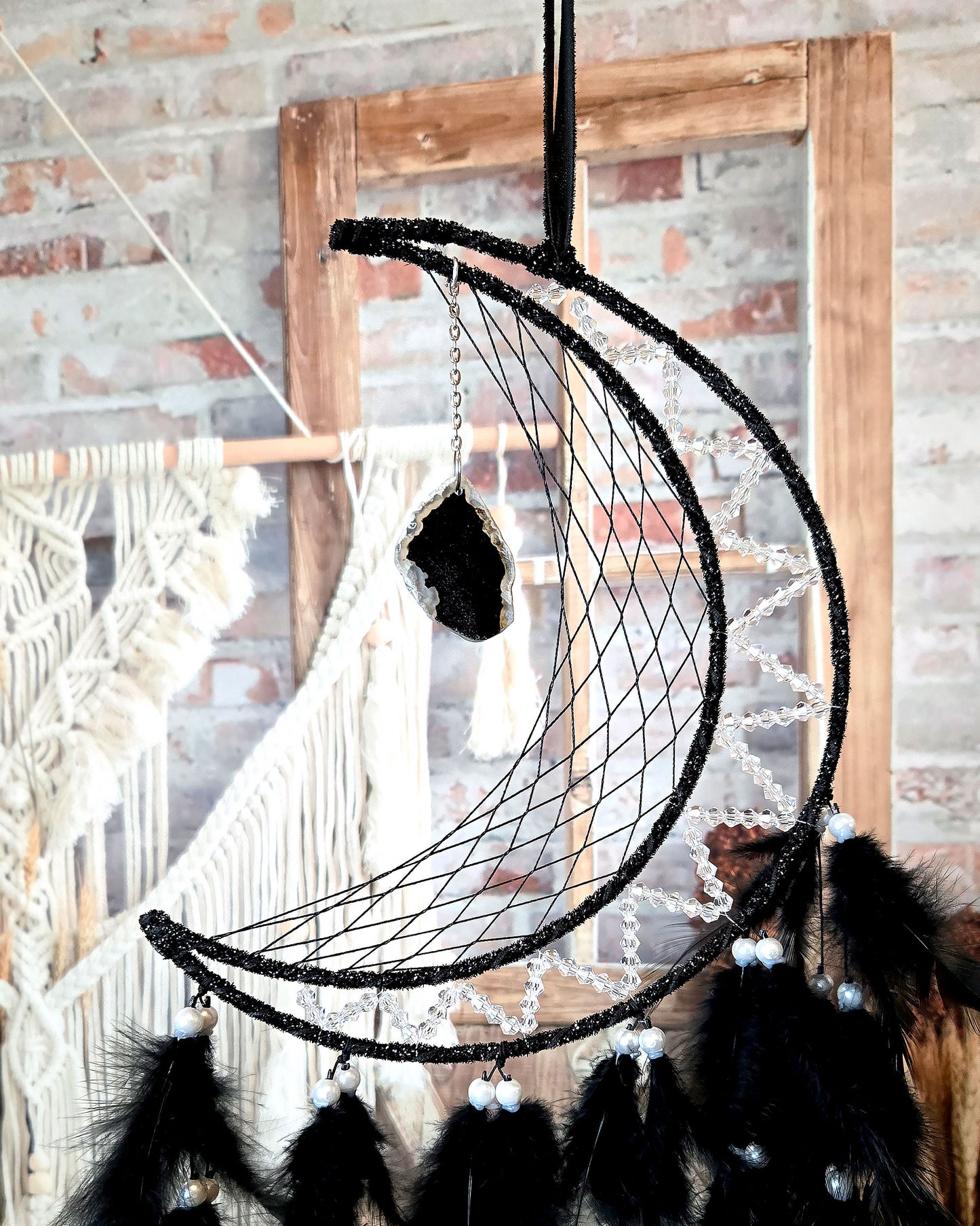 crescent moon dream catcher with black feathers and hanging geode close up