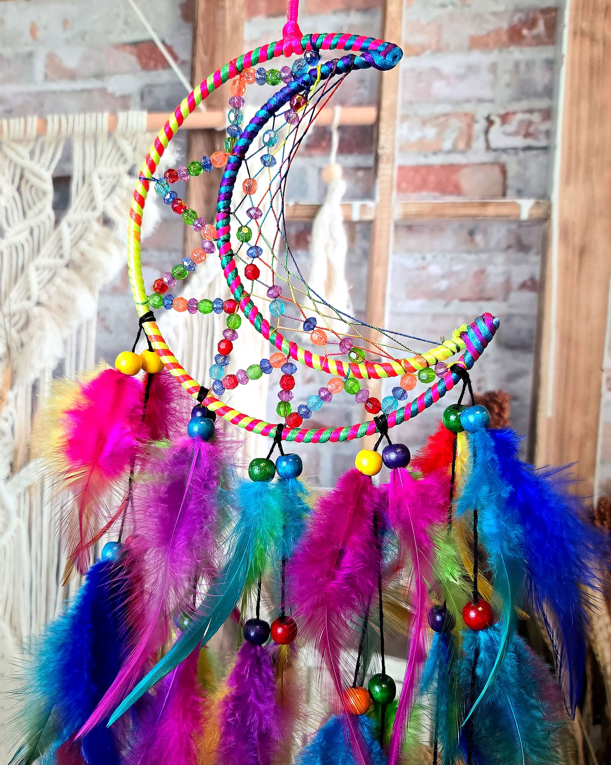 close up of boho hippie home decor moon dream catcher with feathers in rainbow colors 